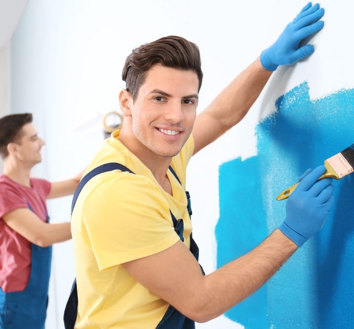 Male decorator painting wall with brush indoors